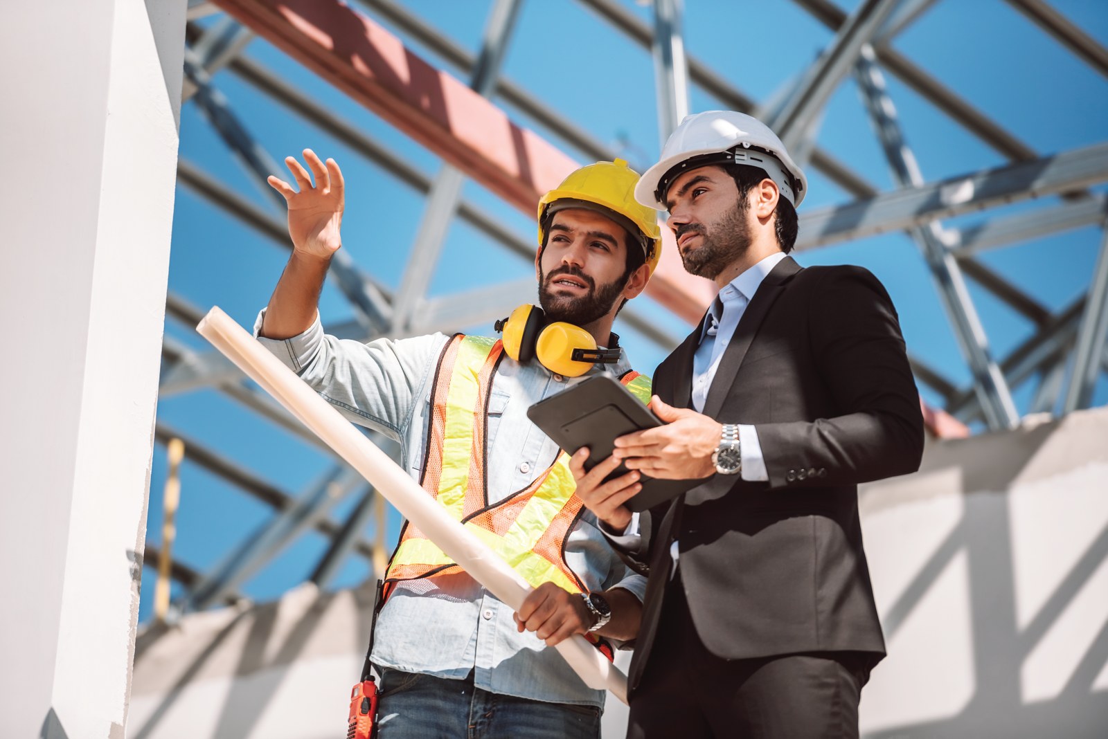 Profesionales revisando planos en una construcción; imagen del brochure de Grupo ACG